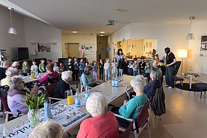 Veranstaltung im Seniorenheim mit Kindern und älteren Menschen in fröhlicher Atmosphäre.