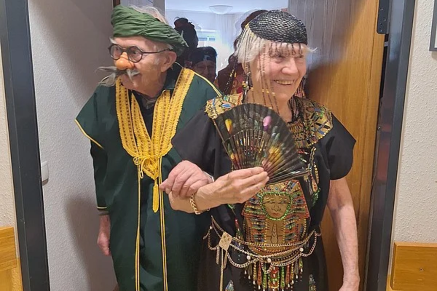 Zwei Personen in ägyptisch inspirierten Kostümen, eine mit grünem Gewand und goldenen Ketten, die andere mit schwarzem Kleid und Fächer.