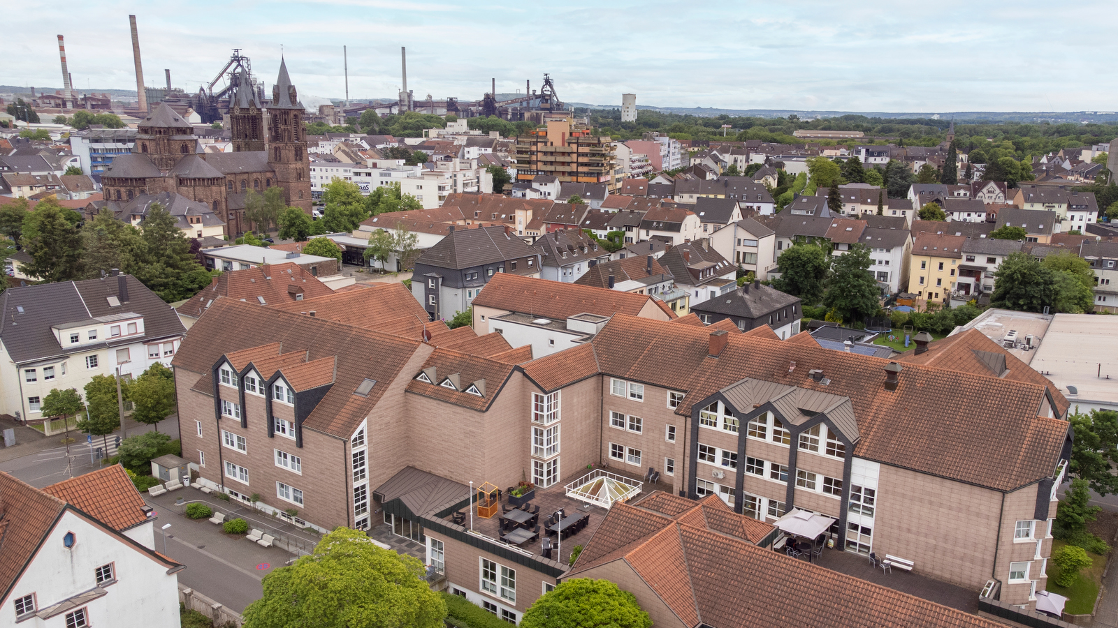 Luftaufnahme einer Stadt mit Wohnhäusern, Kirchen und Industrieanlagen im Hintergrund